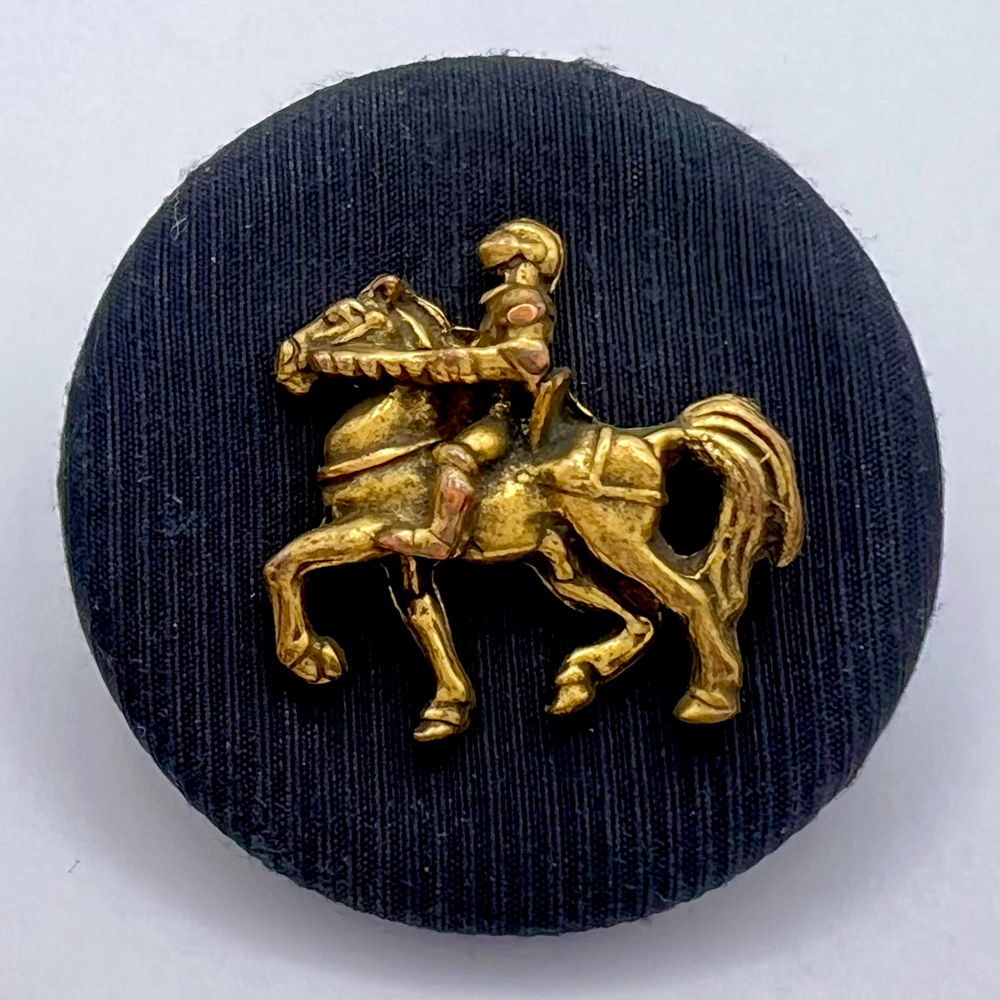 Fabric button with applied knight on horseback.