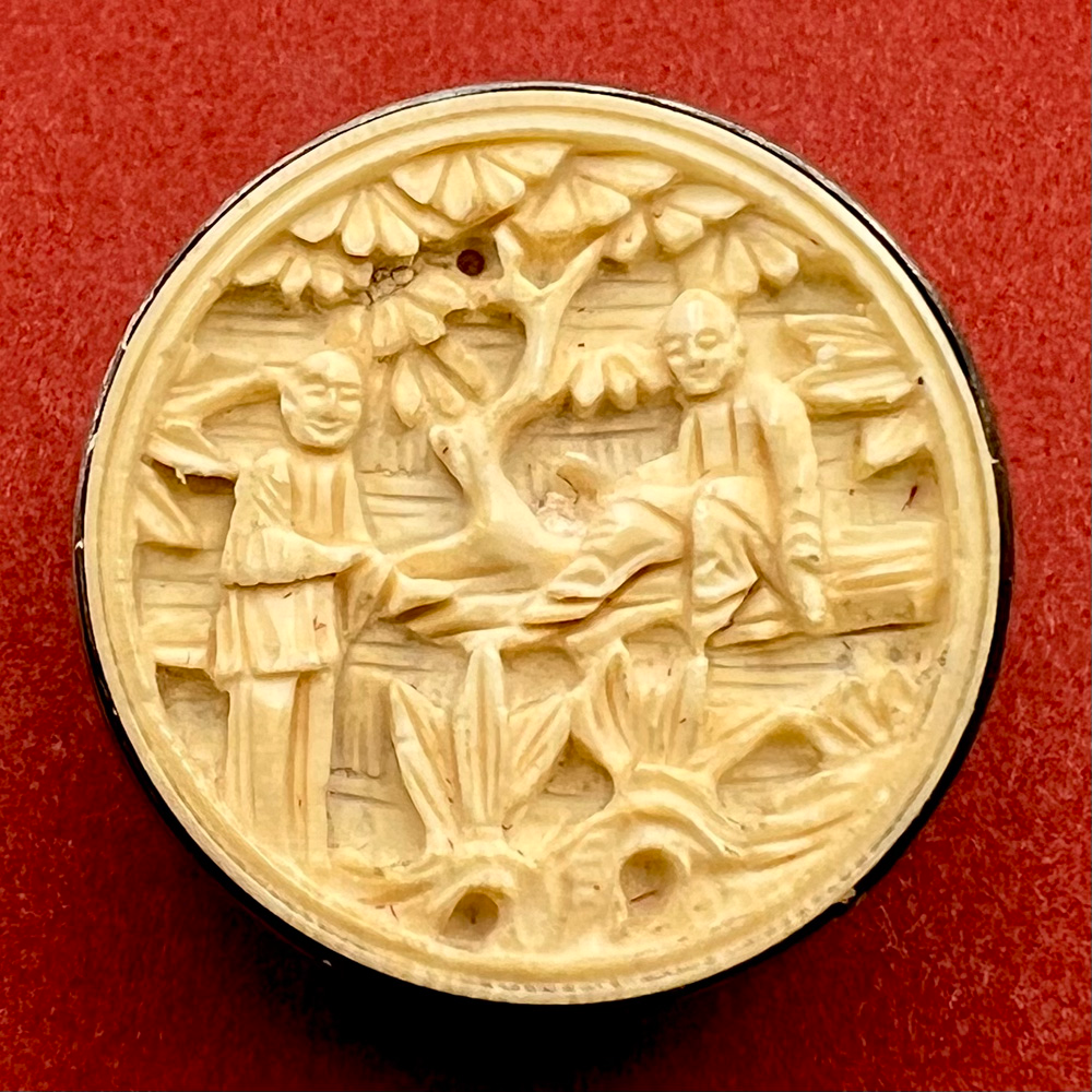 Carved natural material button of men under a tree button.