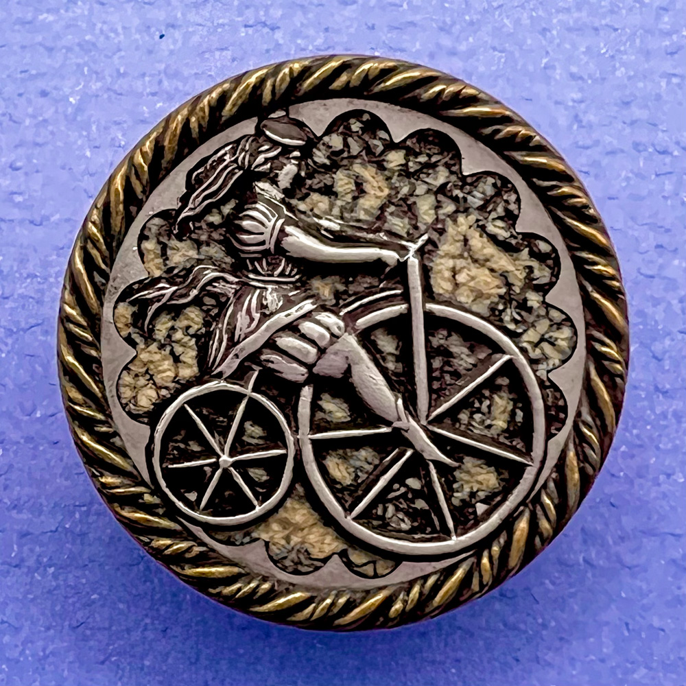 Unusual button of woman riding a penny farthing bicycle.