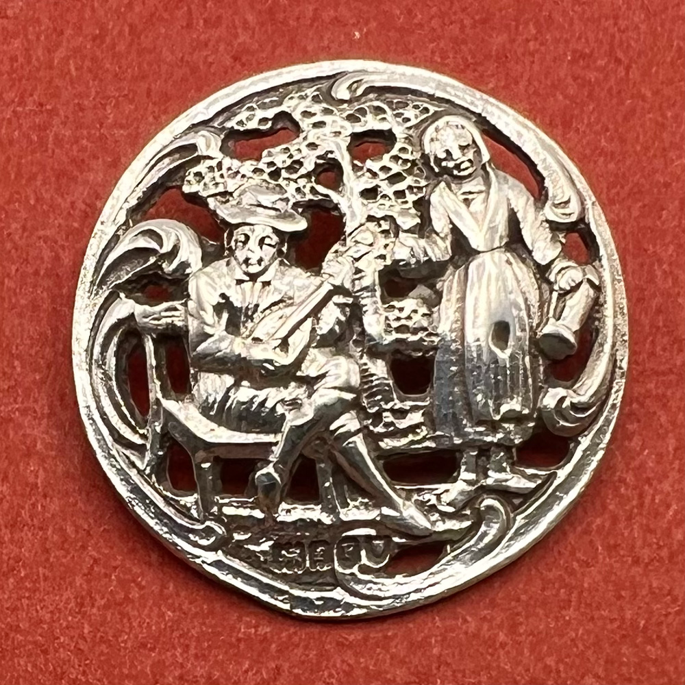 Hallmarked silver button of a man serenading a woman.