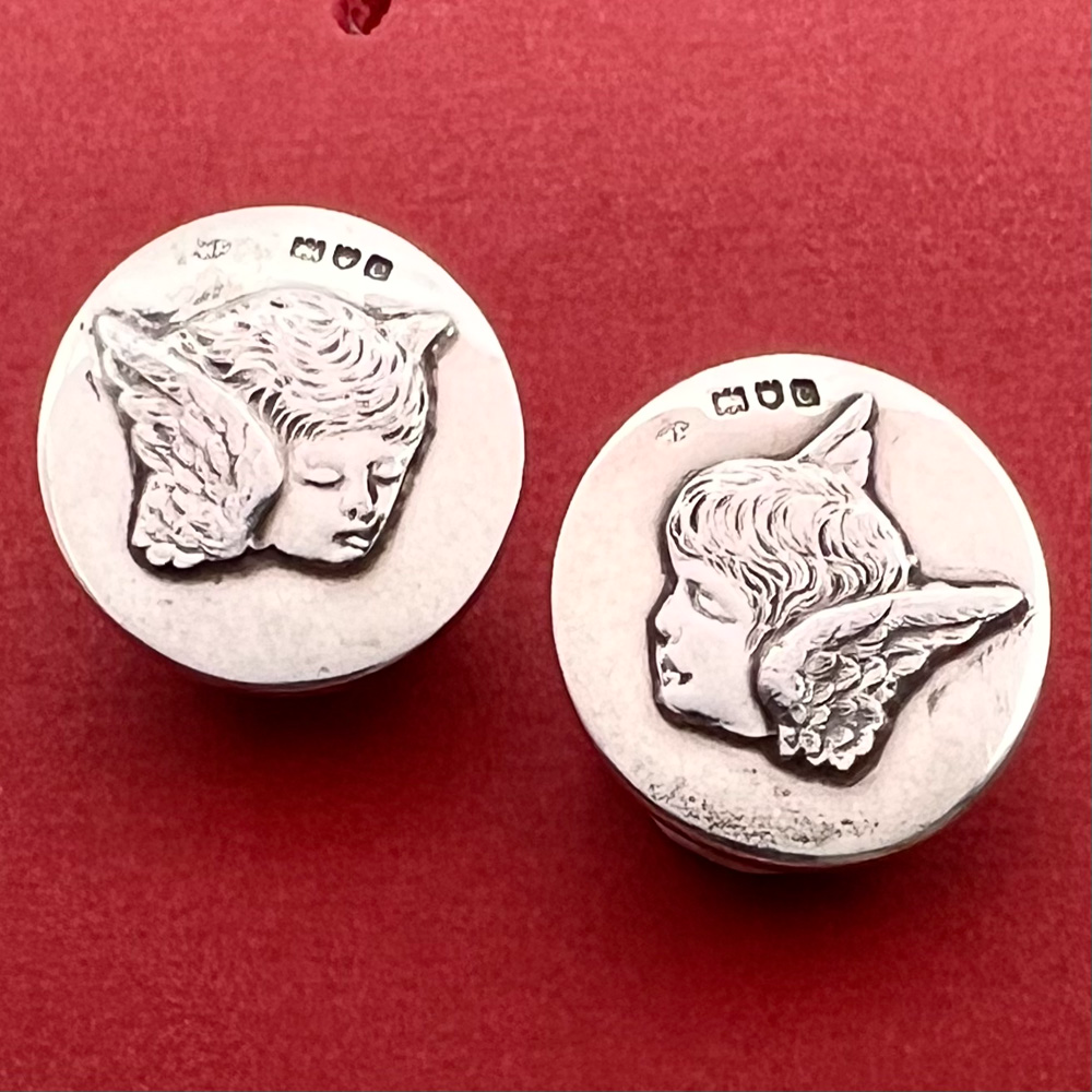 Two hallmarked silver winged cherub head buttons.