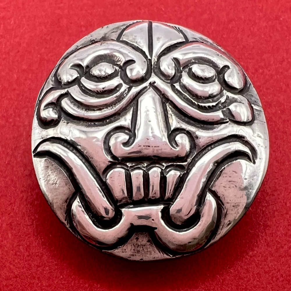 Mexican silver button of a mask face with tusks.