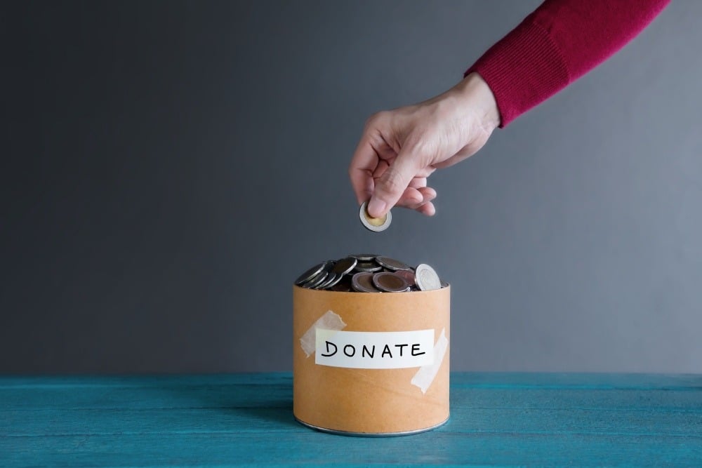 Person putting money in a donation tin