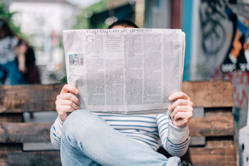 Person reading newspaper on a bench