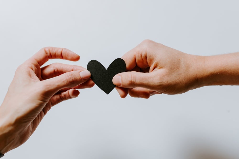 Two hands holding black paper heart