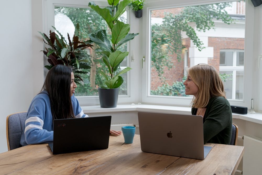 Two women talking in front of their laptops