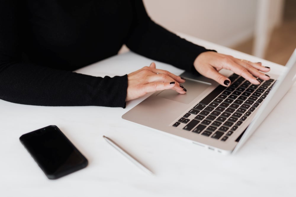 Woman on laptop with mobile phone