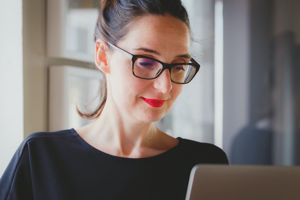 Woman with glasses working on laptop