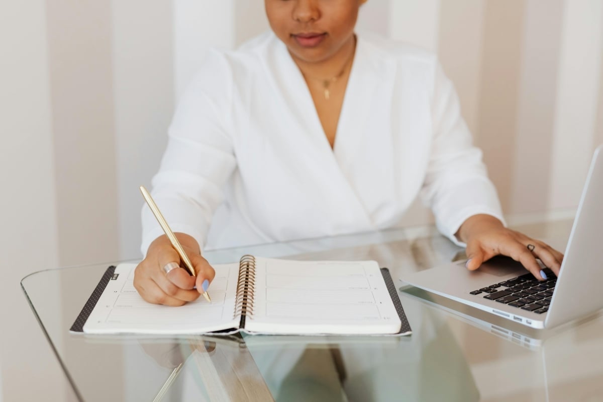Woman working at a laptop and writing notes