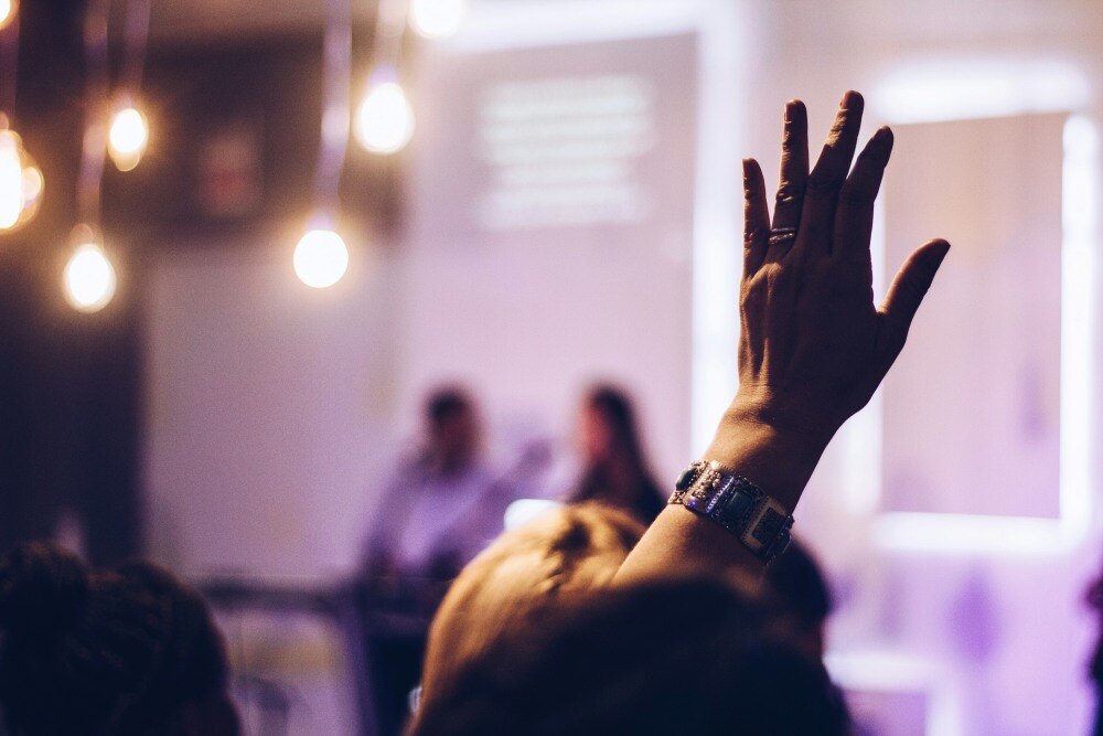 person raising hand to bid at an auction