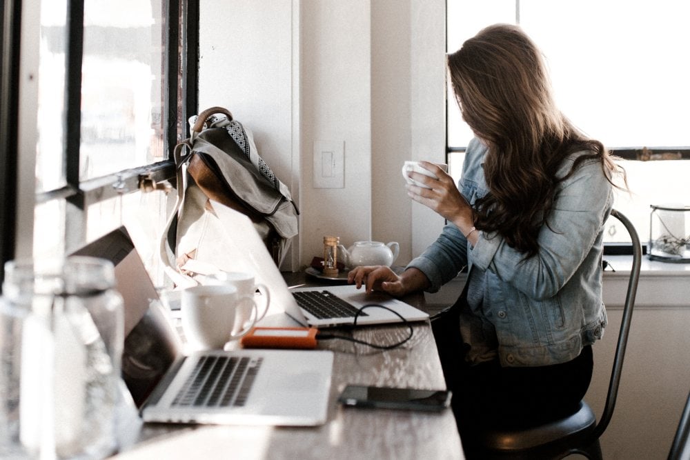 woman working on a laptop drinking coffee